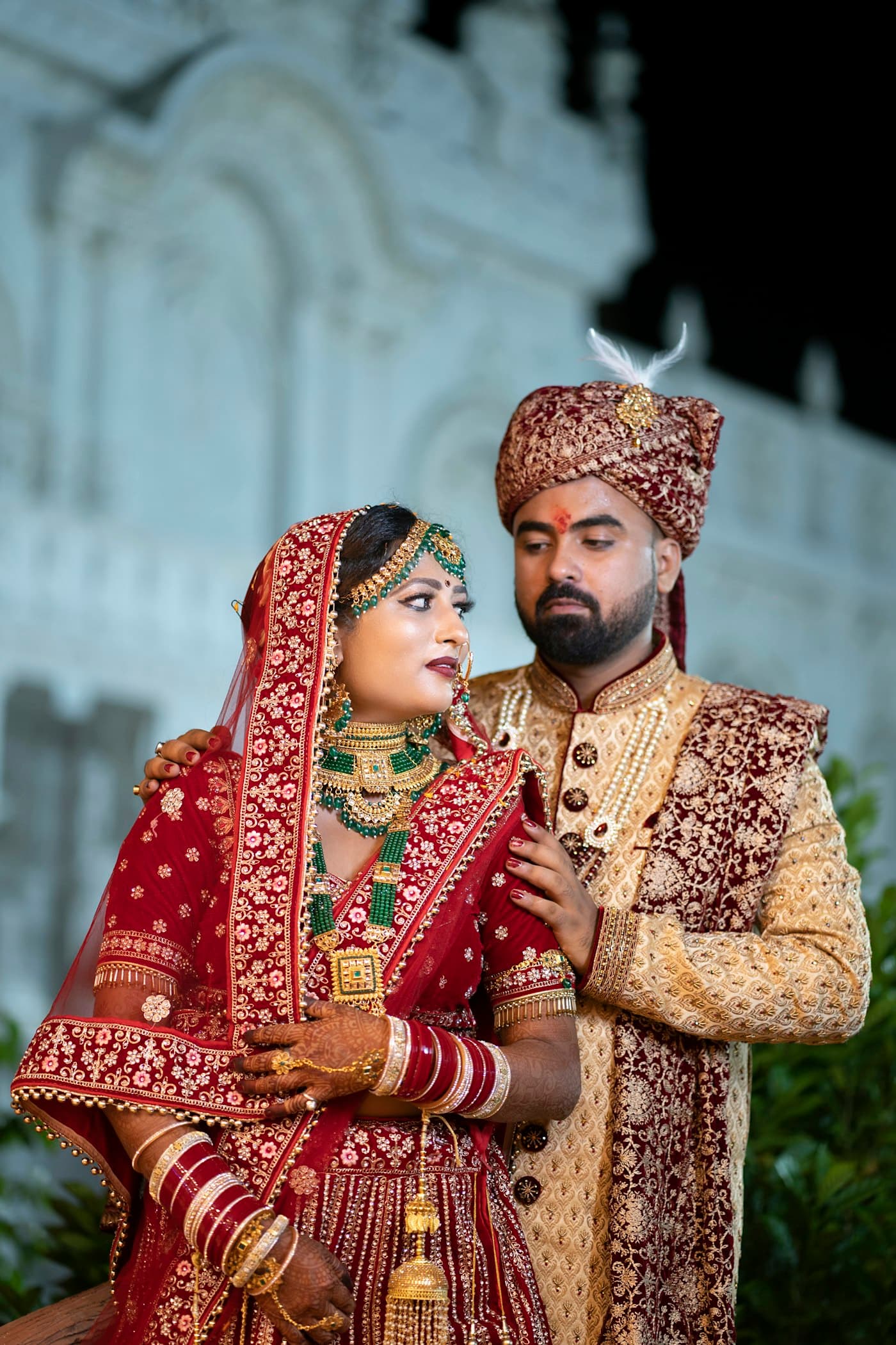 A bride and groom standing together at night in front of an illuminated building